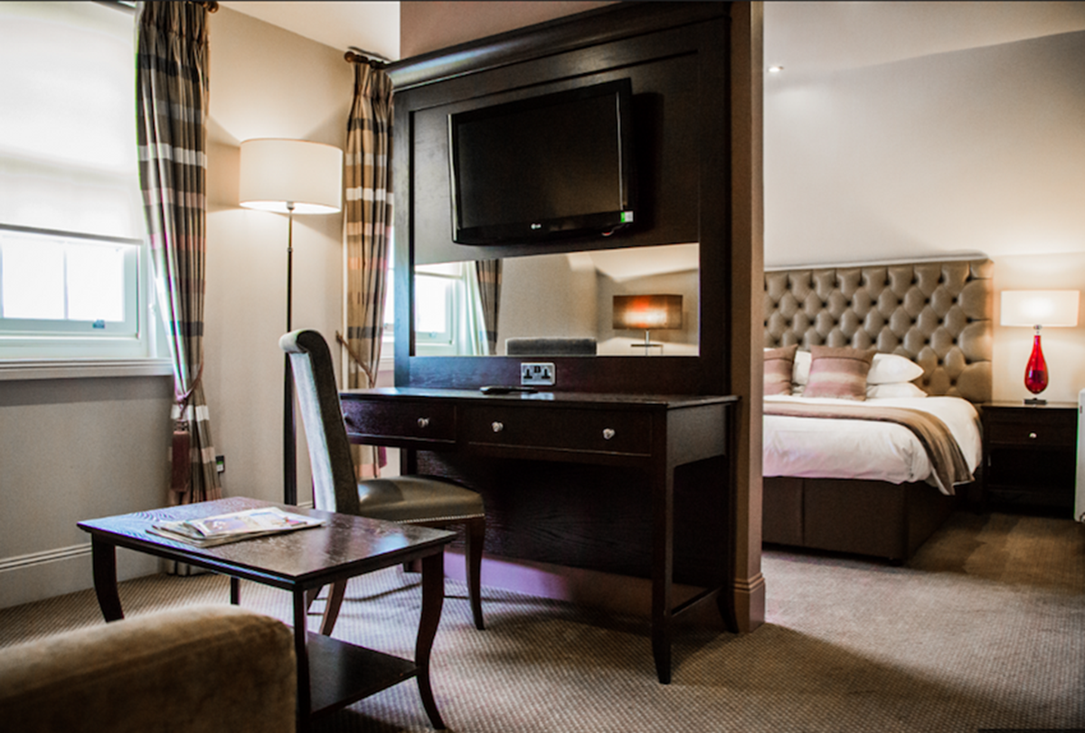 An image that shows a table with a mirror and a television in one of the Dumfries Hotel rooms.