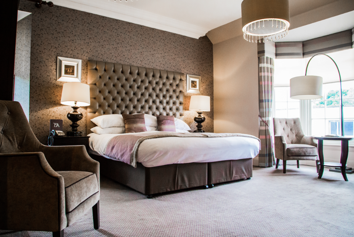 A large hotel bedroom with a bay window that is available at the Dumfries Arms.